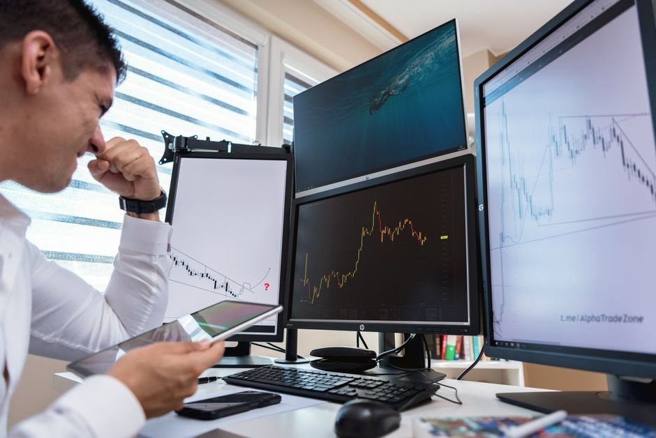 Trader in front of multiple screens reacting to disappointing live results